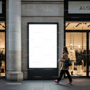 Woman walking past illuminated blank billboard in shopping district