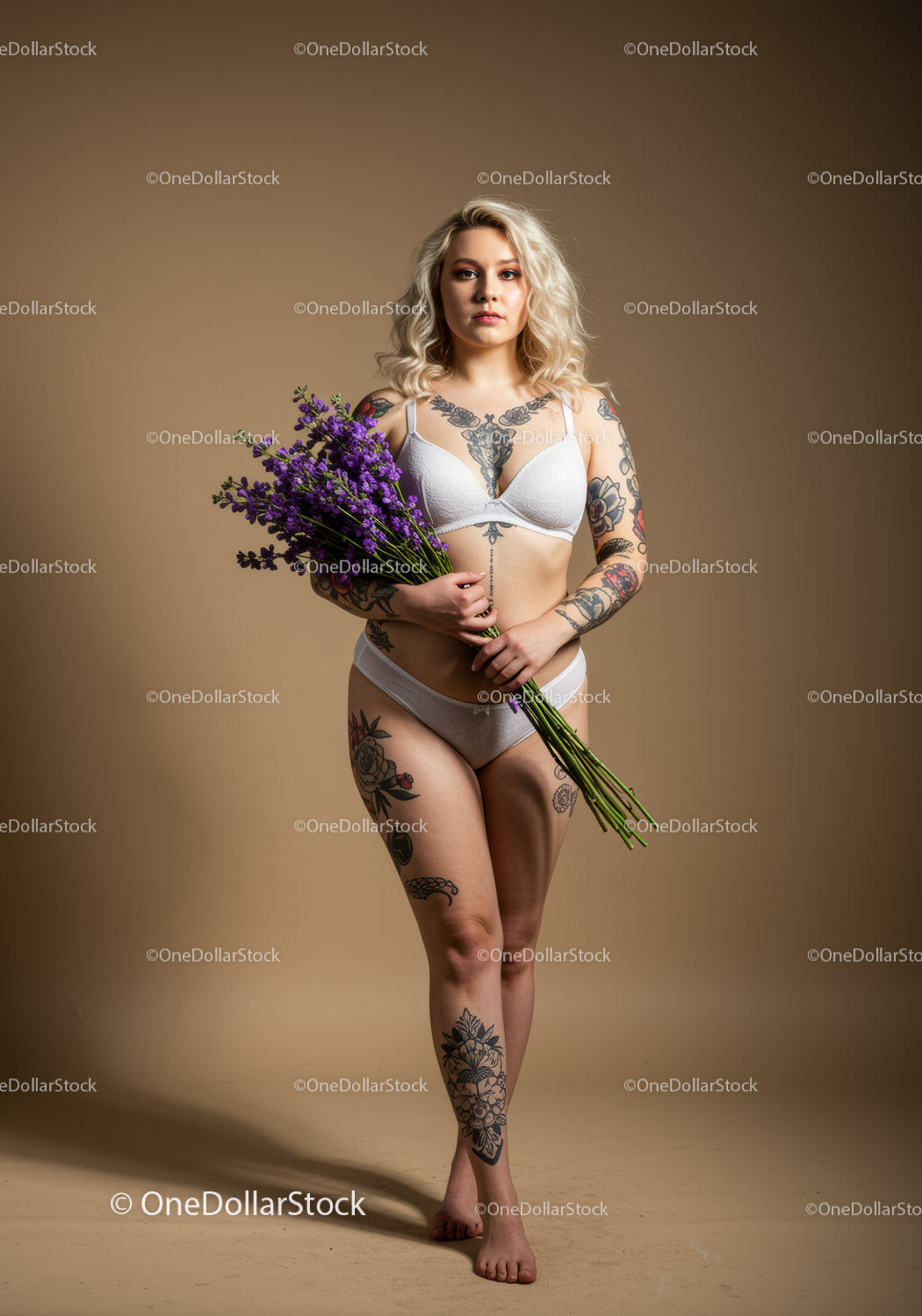 Wytatuowana kobieta trzymająca bukiet lawendy w bieliźnie – portret studyjny