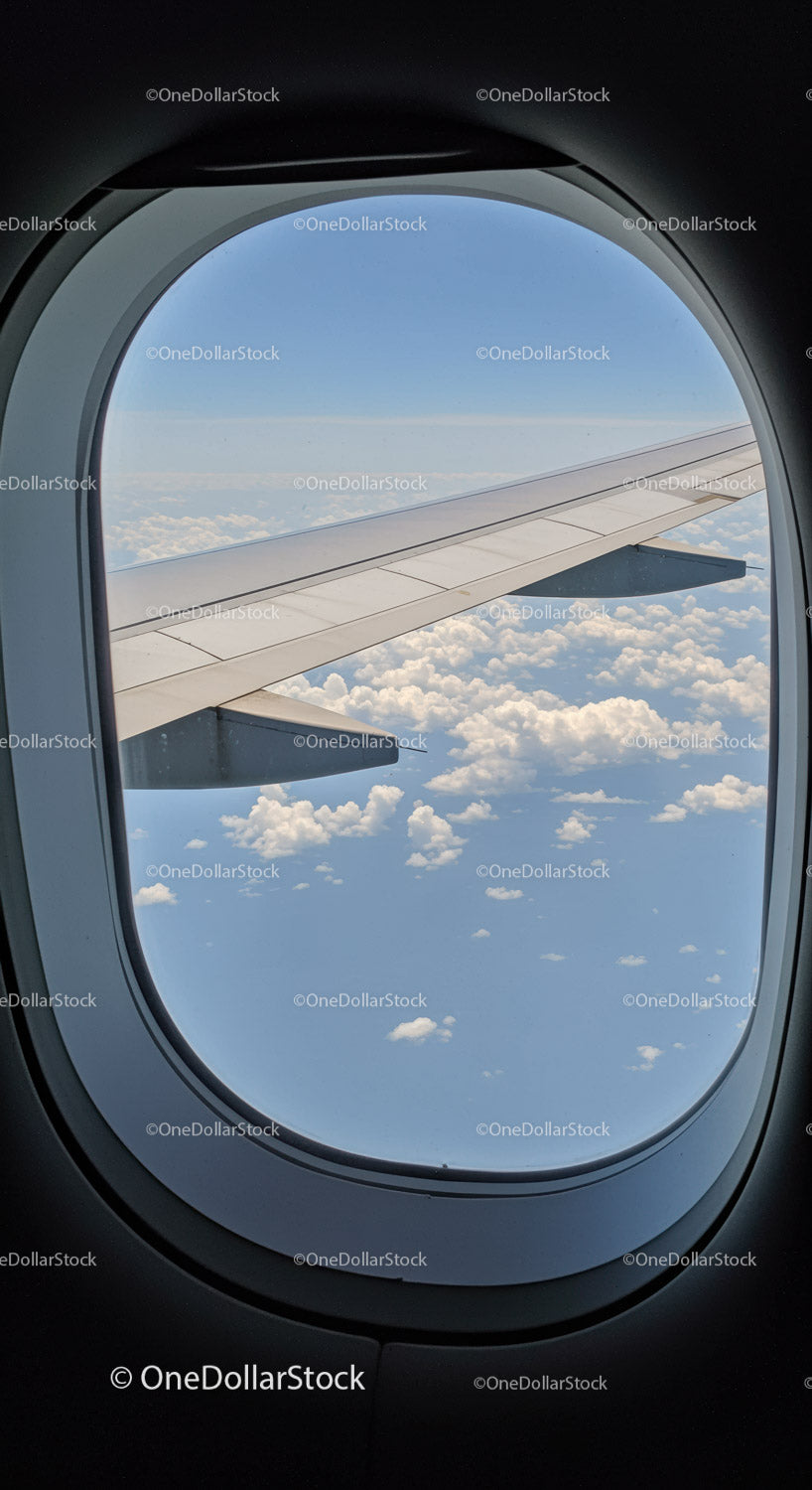Scenic View of Clouds and Wing from Airplane Window with Blue Sky