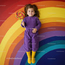 Happy child lying on colorful rainbow floor with lollipop