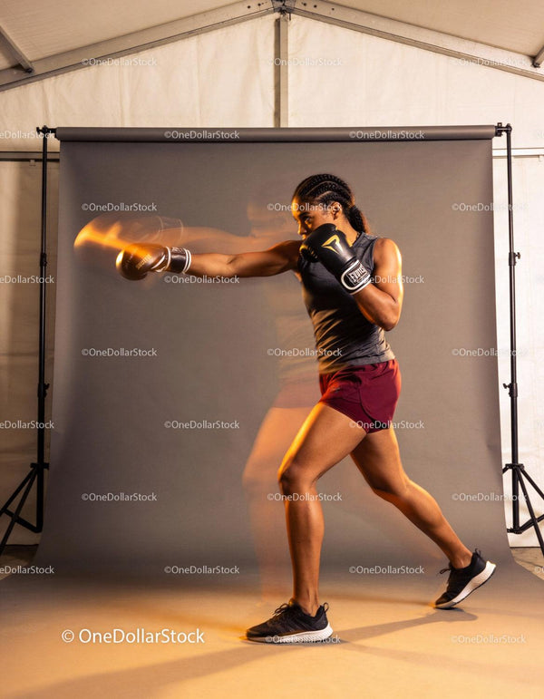 Athletic woman practicing boxing punch indoors
