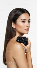 Elegant Young Woman with Brown Hair and Black Grapes in a Studio Portrait