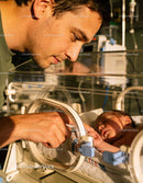 Father Tenderly Watching Newborn Baby in Incubator