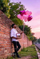 Man Holding Heart Balloons and Chocolates at Sunset