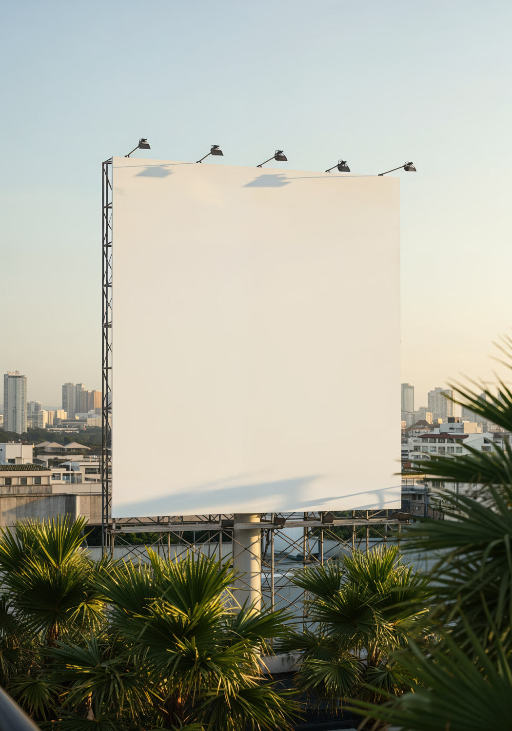 Duży, pusty billboard z widokiem na panoramę miasta o zachodzie słońca