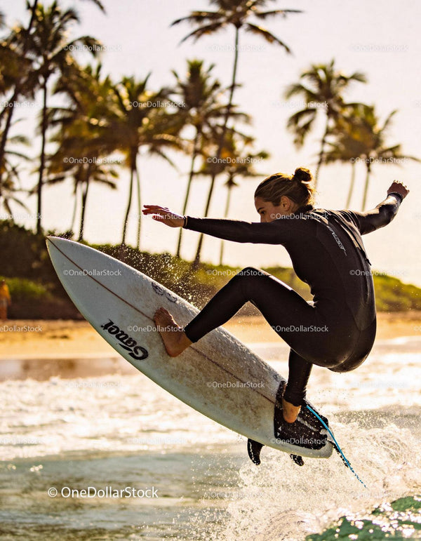 Surfer girl riding wave with palm trees at golden hour