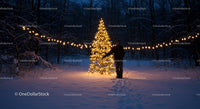 Person standing near illuminated Christmas tree in snowy forest