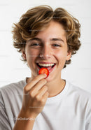 Young Smiling Teen with Strawberry in Close-Up Portrait