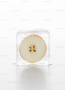 Fresh apple slice frozen inside a clear ice cube