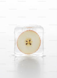Fresh apple slice frozen inside a clear ice cube