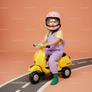 Toddler riding yellow scooter with pink helmet indoors