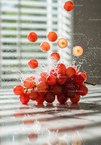 Fresh red grapes splashing on reflective surface