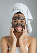 Woman Applying Black Facial Mask with Towel Wrapped Hair