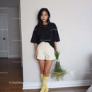 Young Woman in Black Oversized T-Shirt and Beige Shorts Holding Flowers