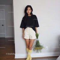 Young Woman in Black Oversized T-Shirt and Beige Shorts Holding Flowers