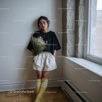 Young Woman with Glasses Holding Flowers in Stylish Casual Outfit