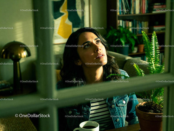 Young woman gazing thoughtfully indoors with coffee cup