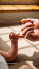 Infant Grasping Adult Finger in Warm Sunlight
