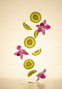 Fresh kiwi slices and pink orchid flowers floating
