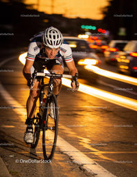 Focused cyclist racing through city streets at dusk
