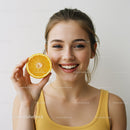 Smiling Woman Holding Fresh Orange Half for Bright Summer Vibe