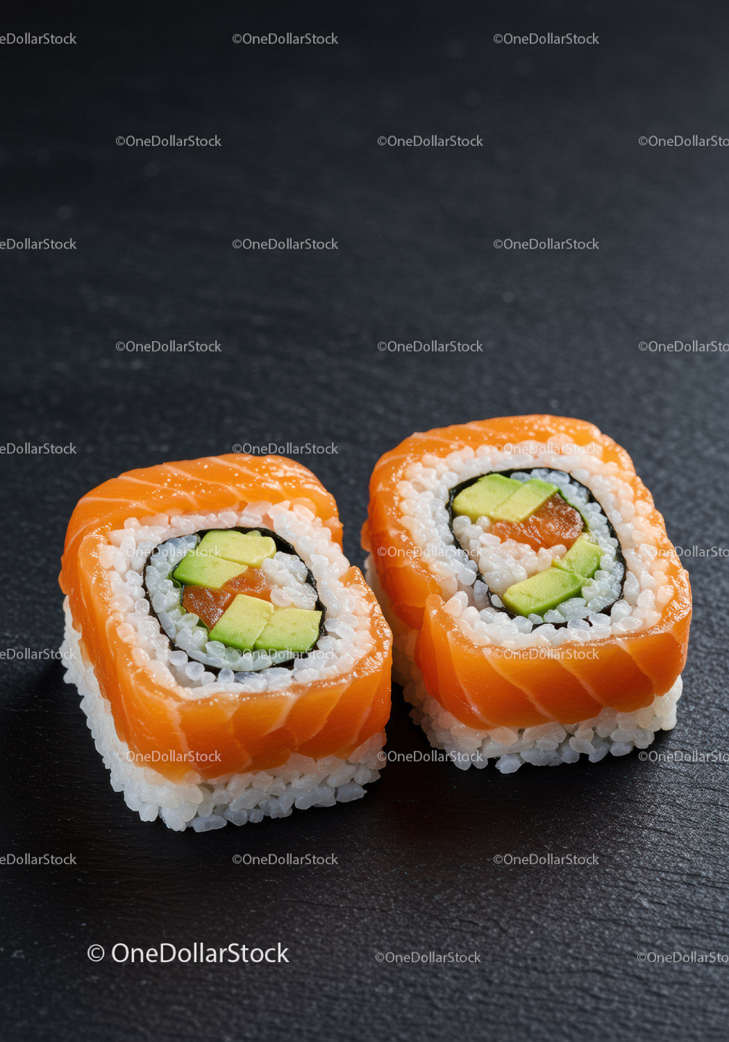 Dwie świeże rolki sushi z łososiem i awokado na czarnym łupku