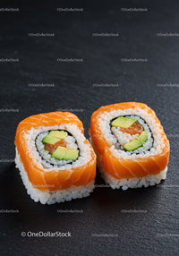 Two Fresh Salmon Avocado Sushi Rolls on Black Slate