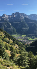 Majestic Mountain Range with Green Forest and Small Village Under Clear Blue Sky
