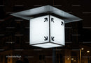Illuminated cube street sign with black arrows at night