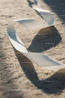 Close-up of White Plastic Ribbon Waste on Sandy Beach
