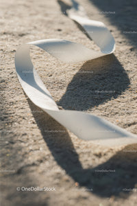 Close-up of White Plastic Ribbon Waste on Sandy Beach
