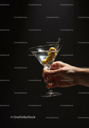 Hand Holding Martini Glass with Olive Garnish