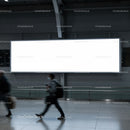 People walking past a large blank city billboard
