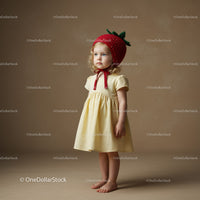 Little girl in yellow dress wearing strawberry hat