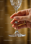 Elegant hand holding crystal wine glass with ring detail