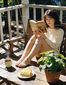 Young woman enjoying book and coffee on porch swing