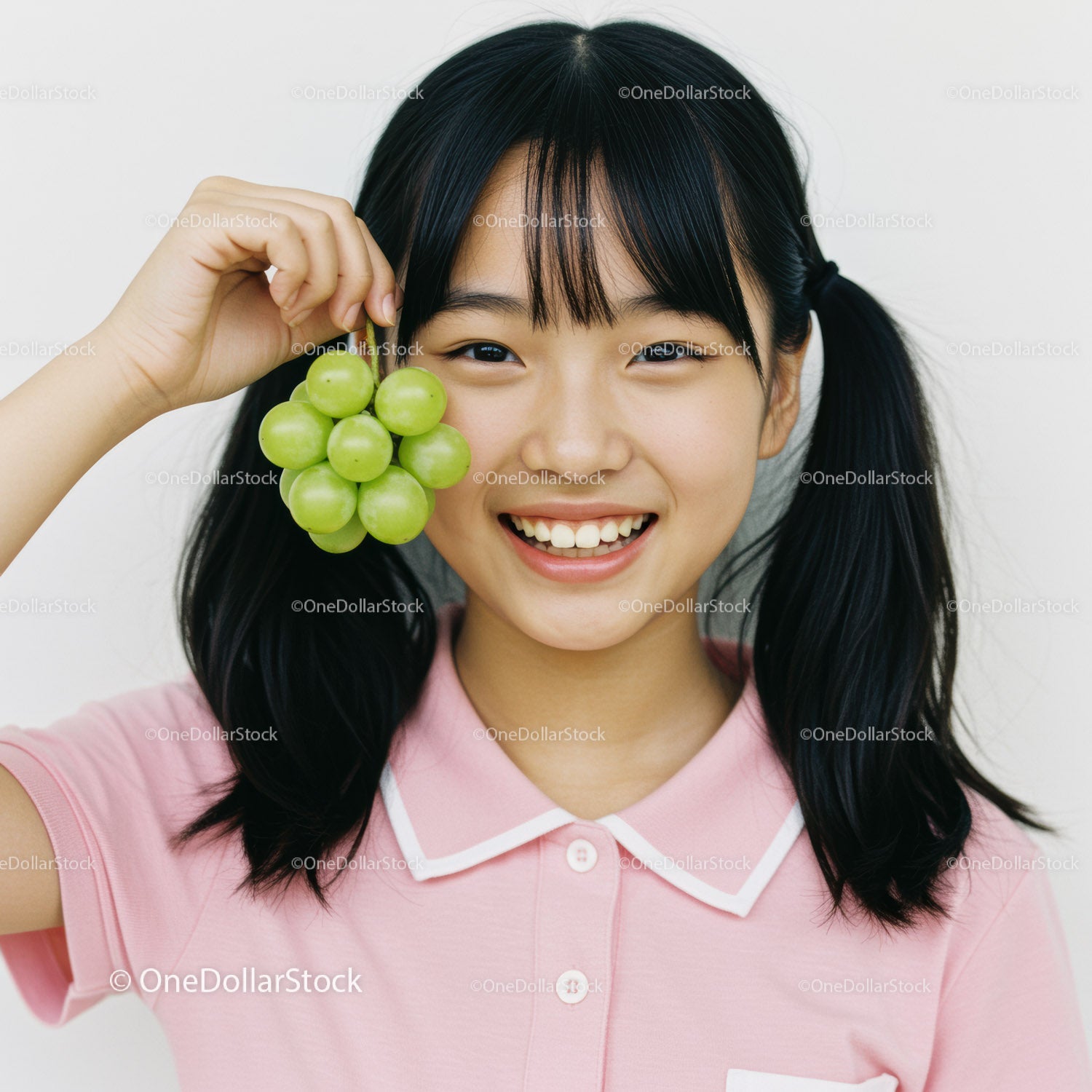Happy Young Girl Holding Fresh Green Grapes in Casual Pink Polo