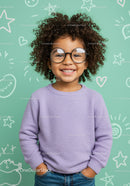 Smiling child with curly hair and round glasses in pastel room