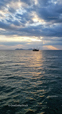 Serene Sunset Over Ocean with Sailing Boat and Cloudy Sky
