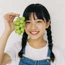 Happy Girl Holding Green Grapes with Bright Smile in Casual Outfit