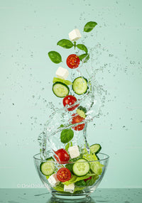 Fresh vegetable salad with splashing water in glass bowl