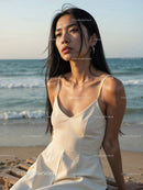 Elegant Woman in White Dress Sitting by Relaxing Seaside Landscape