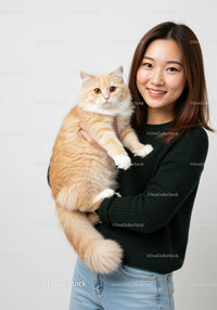 Smiling woman holding fluffy ginger cat indoors
