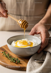 Honey Dripping into Yogurt Bowl with Fresh Herbs on Wooden Board
