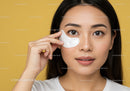 Young Woman Applying Eye Patch for Skin Care with Yellow Background