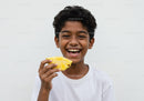 Joyful Boy Eating Pineapple Slice with Bright Smile