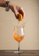 Hand Squeezing Fresh Lemon Into Splashing Drink Glass