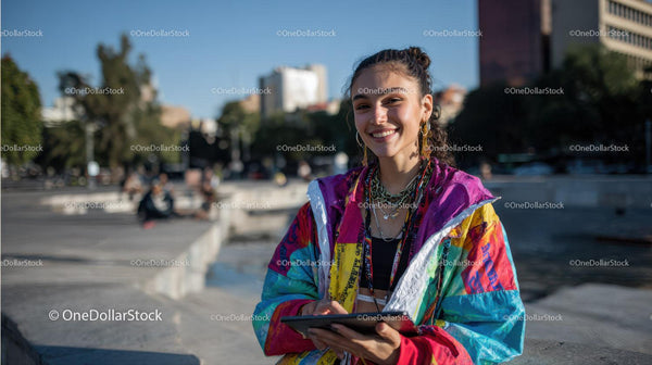 Vibrant Young Woman in Colorful Windbreaker Outdoors Holding Tablet