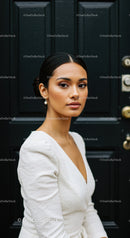 Elegant woman in white dress posing against black door