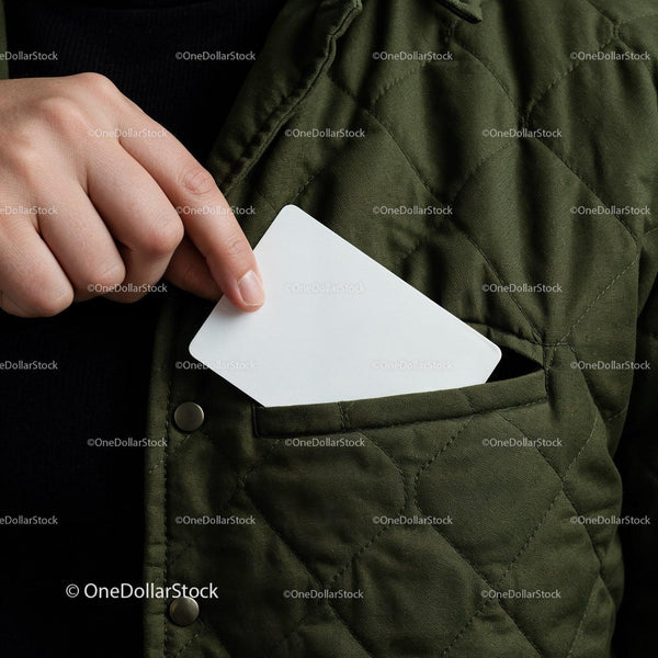 Person putting blank card into green quilted jacket pocket JPG Mockup Image